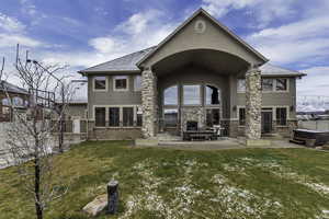 Back of house featuring stucco siding, a hot tub, and a patio area