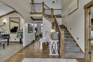 Entrance foyer featuring a high ceiling, arched walkways, ornamental molding, and light wood-style floors