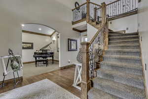 Stairway with hardwood / wood-style flooring, arched walkways, ornamental molding, and recessed lighting