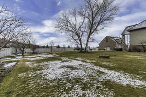 Snowy yard featuring a trampoline, a fenced backyard, and an outdoor fire pit