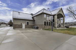 Rear view of property with stucco siding, a lawn, a patio, and brick siding