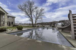 View of swimming pool with a fenced backyard, a water slide, and patio surround
