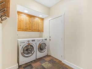 Laundry room with dark stone finish flooring, cabinet space, washing machine and clothes dryer, and recessed lighting