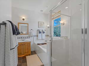 Full bath with vanity, a shower stall, a garden tub, dark stone finish floors, and decorative backsplash