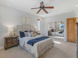 Bedroom with light carpet, a closet, and ceiling fan