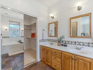 Bathroom featuring double vanity, a bath, and stone tile floors