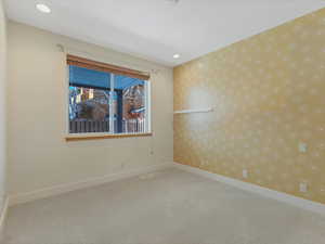 Empty room with light colored carpet and wallpapered walls