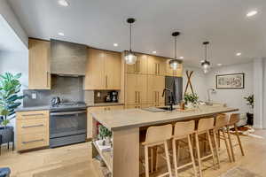 Kitchen with light wood finish cabinetry, stainless steel range with gas stovetop, and light wood-type flooring