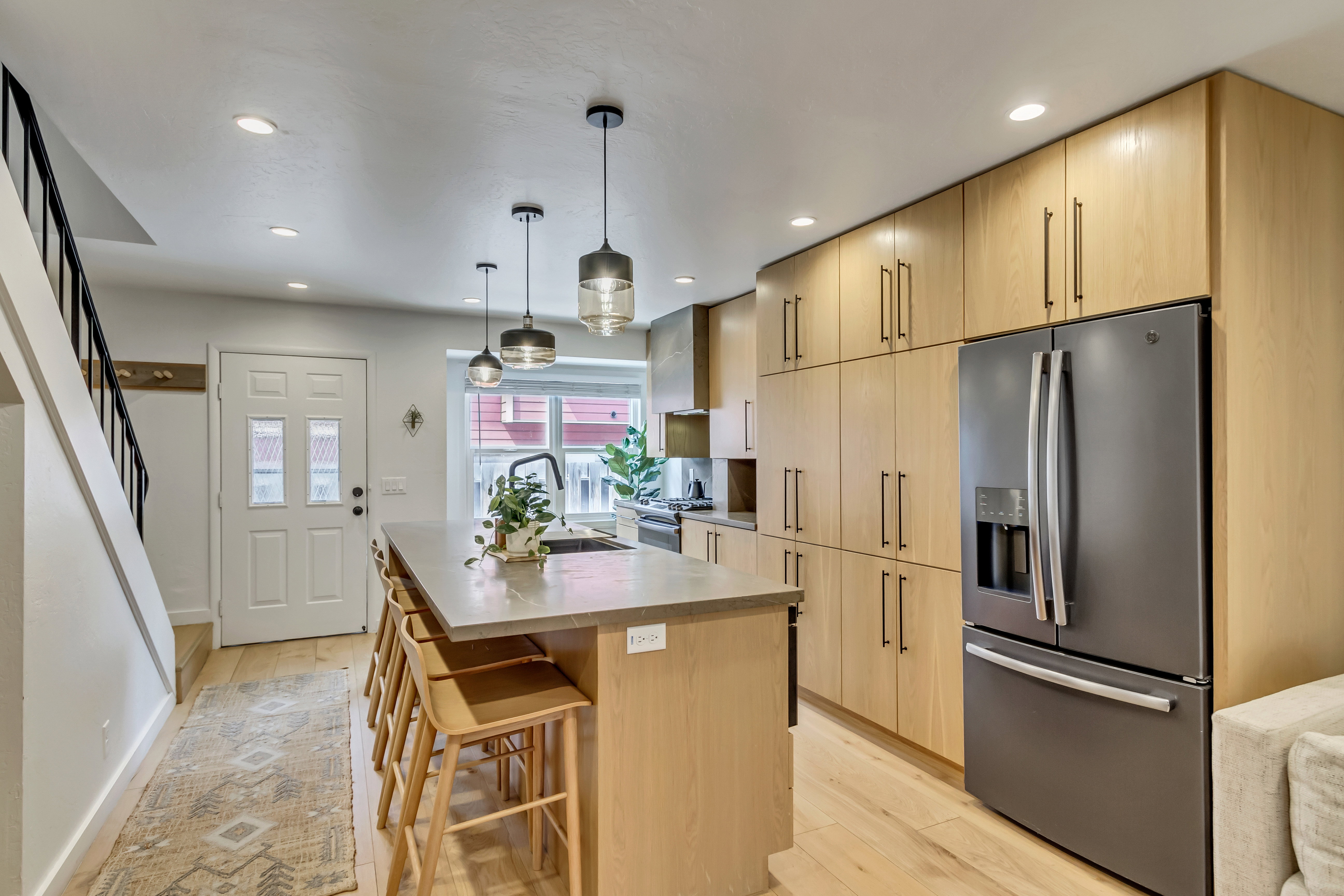 Kitchen with light wood finish cabinets, stainless steel appliances, a kitchen island with sink, and light wood-style floors