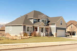 Craftsman-style house featuring covered porch, a garage, driveway, and a front yard
