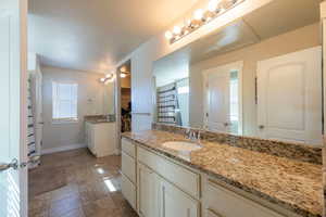 Full bathroom with two vanities, a shower stall, light tile patterned flooring, and a walk in closet