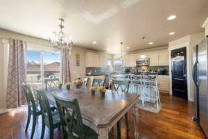 Dining area featuring dark wood finished floors, a textured ceiling, and hanging lights