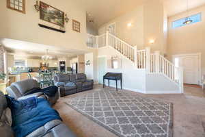 Living room with healthy amount of natural light, light colored carpet, a chandelier, and a high ceiling