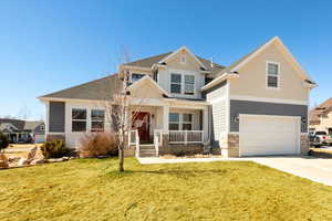 Craftsman-style home with a porch, a front yard, concrete driveway, and an attached garage