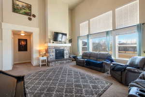 Living room with carpet flooring, a fireplace, and a high ceiling