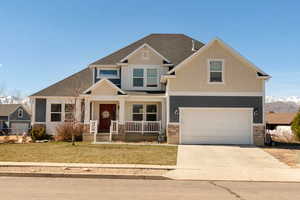 Craftsman-style home with covered porch, driveway, an attached garage, and a front lawn