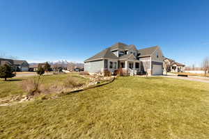 View of front of property with a front yard, driveway, a mountain view, and covered porch