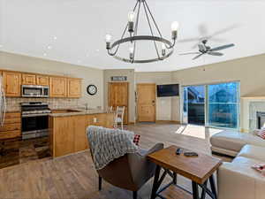 Living room and kitchen area featuring wood-style flooring and trim and a tiled fireplace