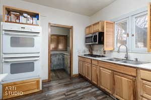 Kitchen featuring stainless steel appliances, light countertops, and dark wood-style floors