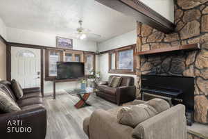 Living area with a textured ceiling, a ceiling fan, and wood finished floors