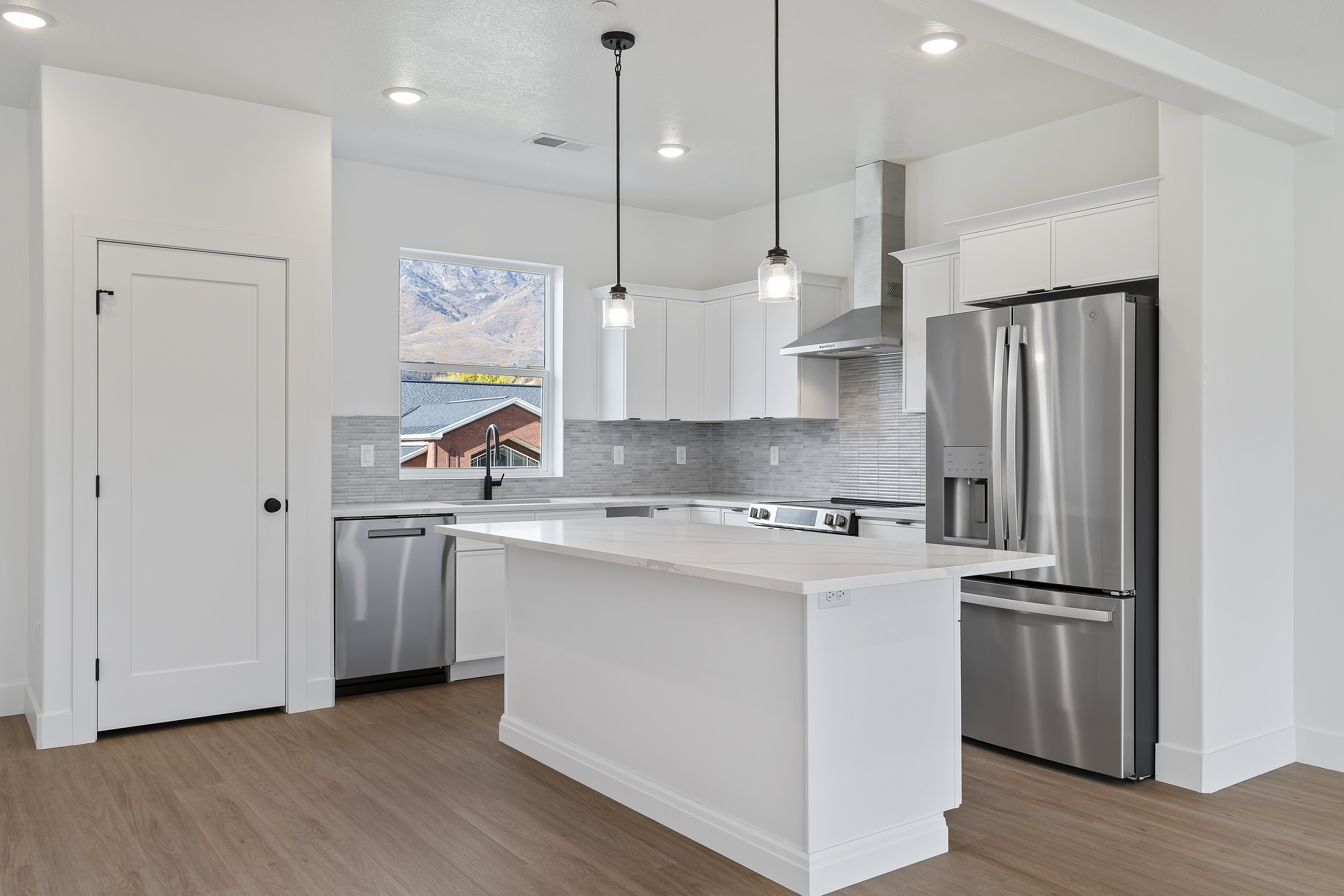 Kitchen with stainless steel appliances, white cabinets, tasteful backsplash, and light wood finished floors