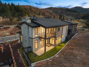 Rear view of property featuring a patio area, a mountain view, a chimney, roof with shingles, and board and batten siding