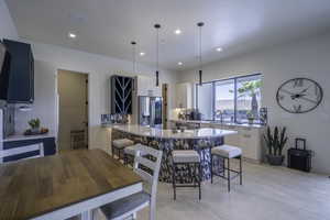 Kitchen with a kitchen bar, light stone countertops, a peninsula, and decorative light fixtures