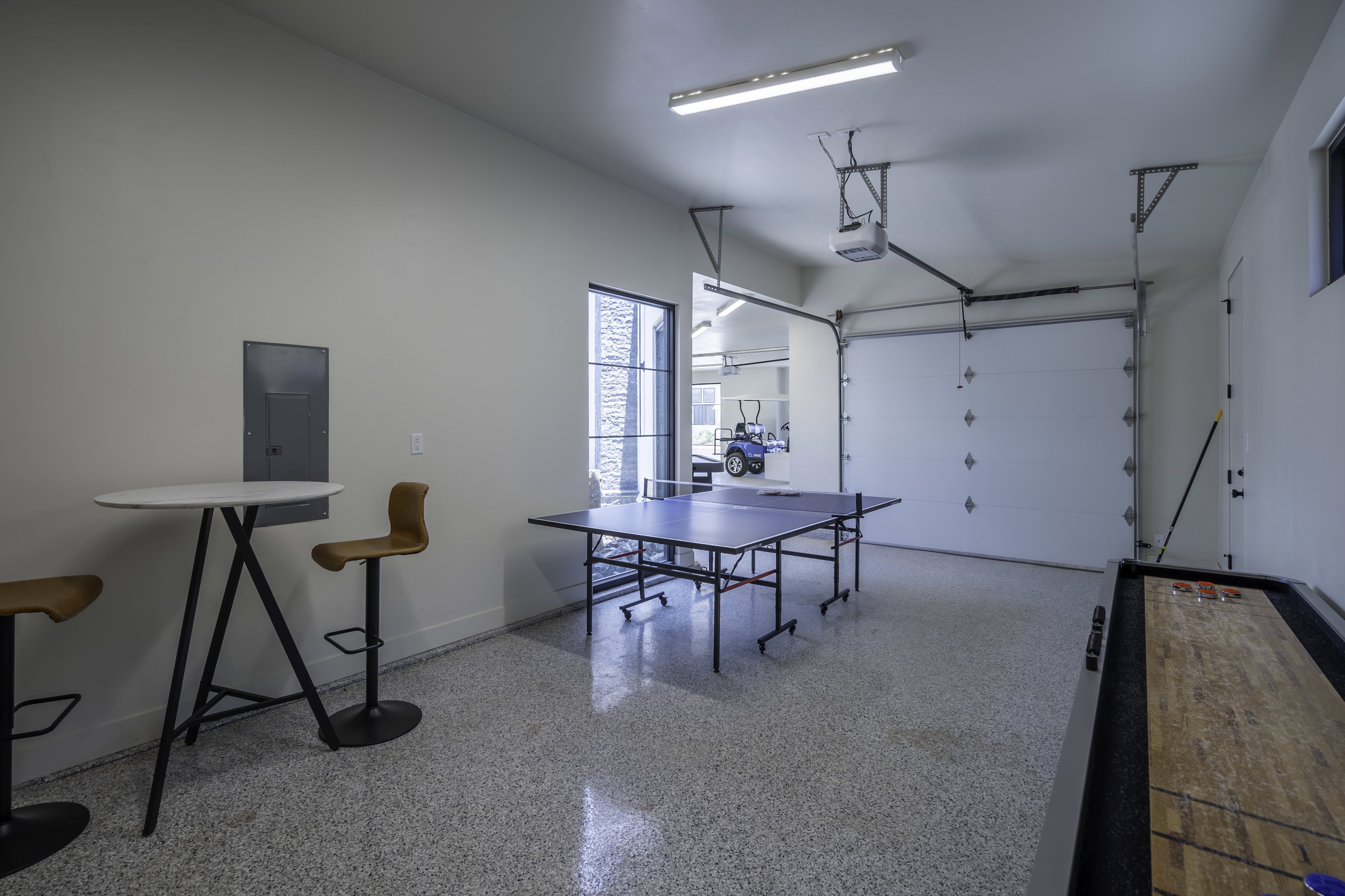 Game room with dark speckled floor, a garage, and electric panel