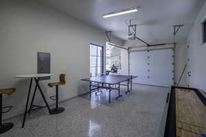 Game room with dark speckled floor, a garage, and electric panel