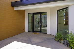 View of exterior entry featuring stucco siding and a patio