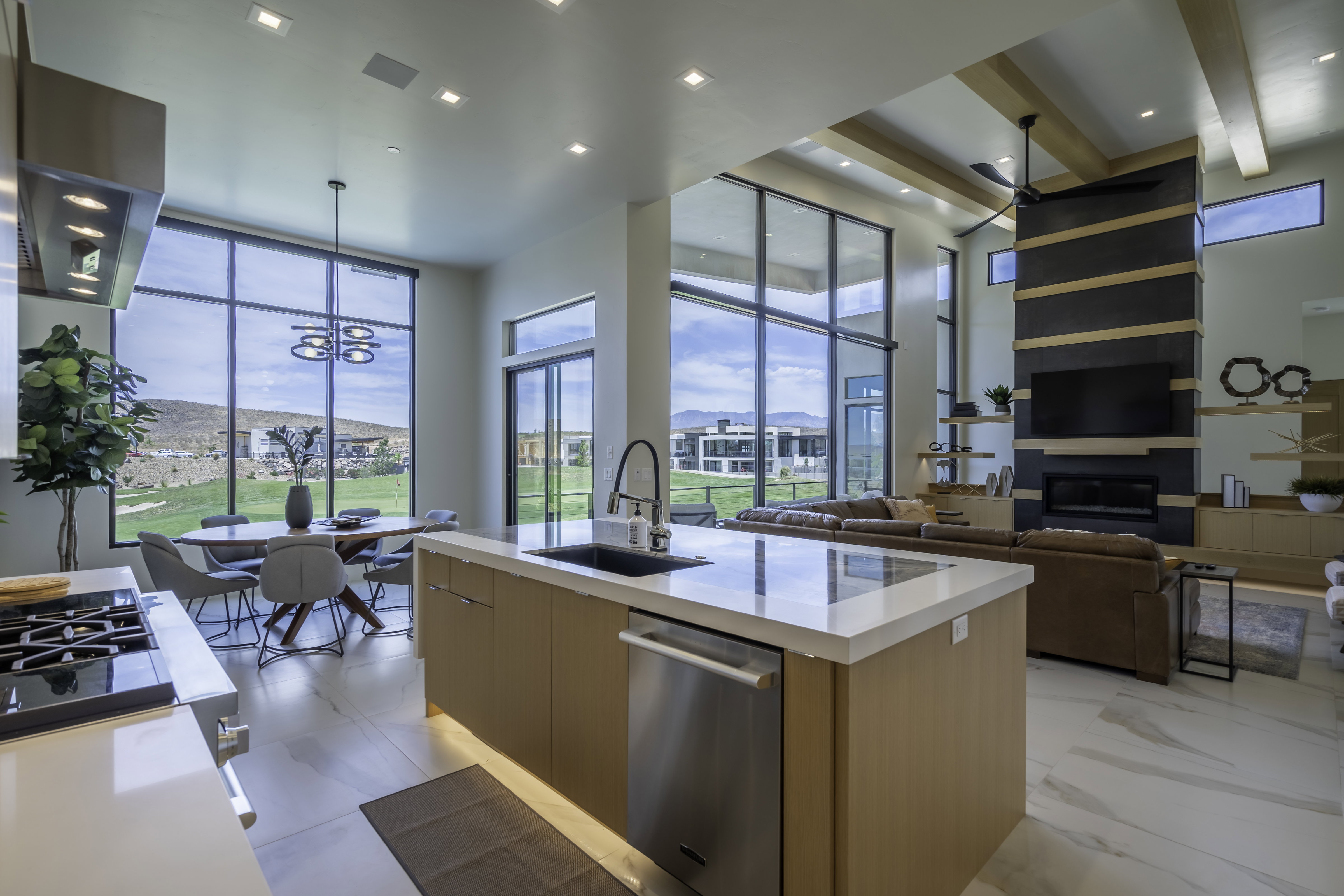 Kitchen with modern cabinets, light stone counters, a kitchen island with sink, stainless steel appliances, and range hood