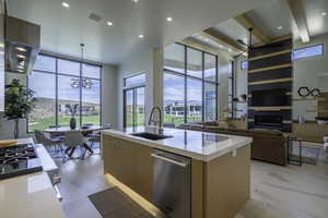 Kitchen with modern cabinets, light stone counters, a kitchen island with sink, stainless steel appliances, and range hood