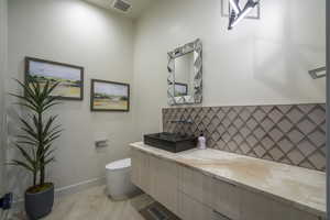 Bathroom with vanity and tasteful backsplash