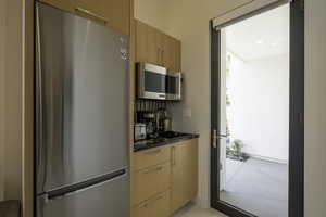 Kitchen with stainless steel appliances, modern cabinets, and light wood finish cabinets