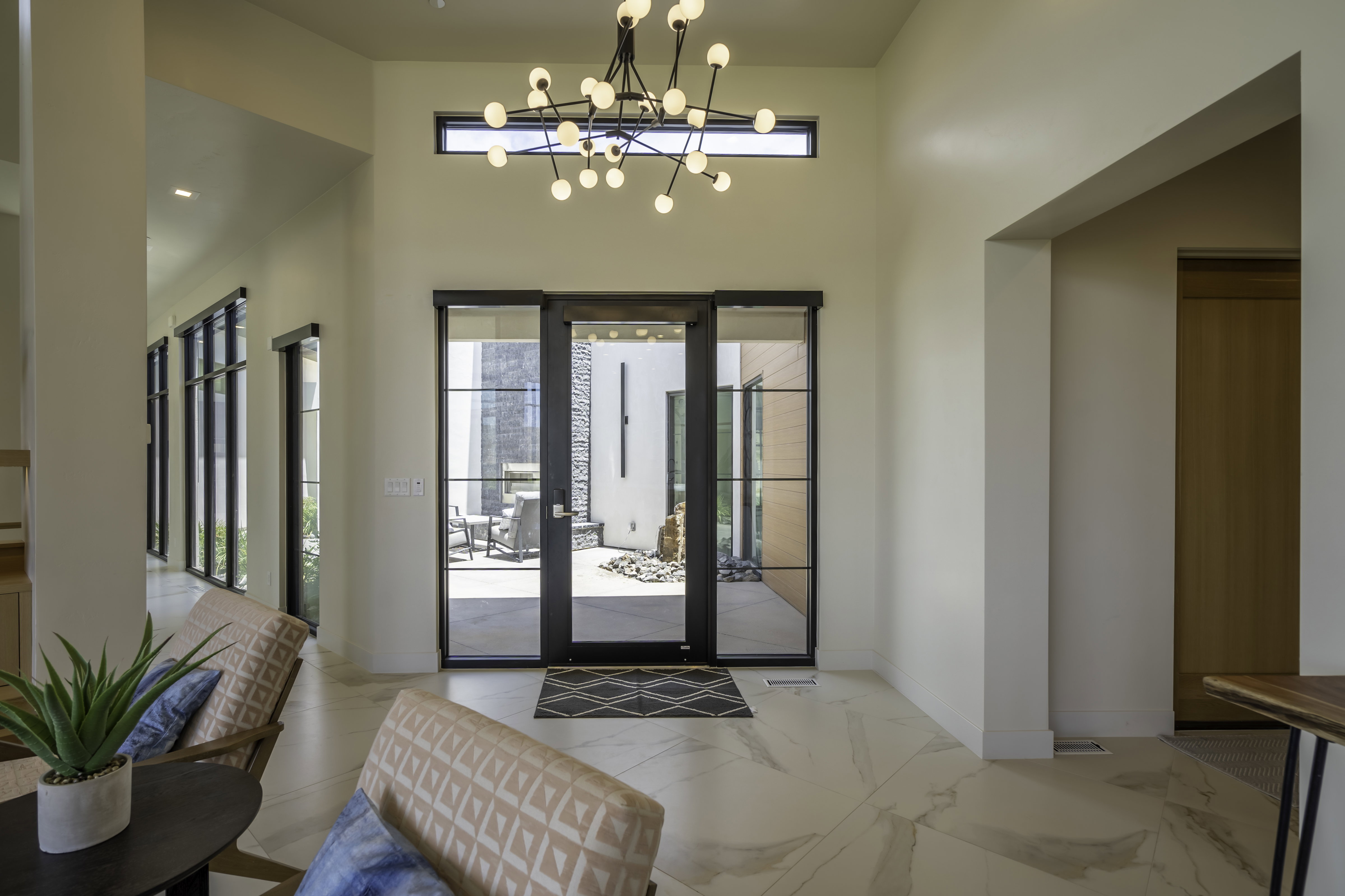 Foyer entrance featuring hanging lights, light marble finish floors, and a high ceiling