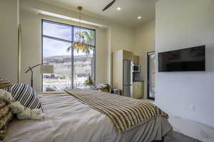 Bedroom featuring a high ceiling, freestanding refrigerator, multiple windows, recessed lighting, and a ceiling fan