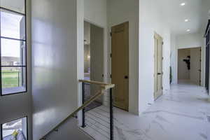 Hallway featuring an upstairs landing, recessed lighting, and light marble finish flooring