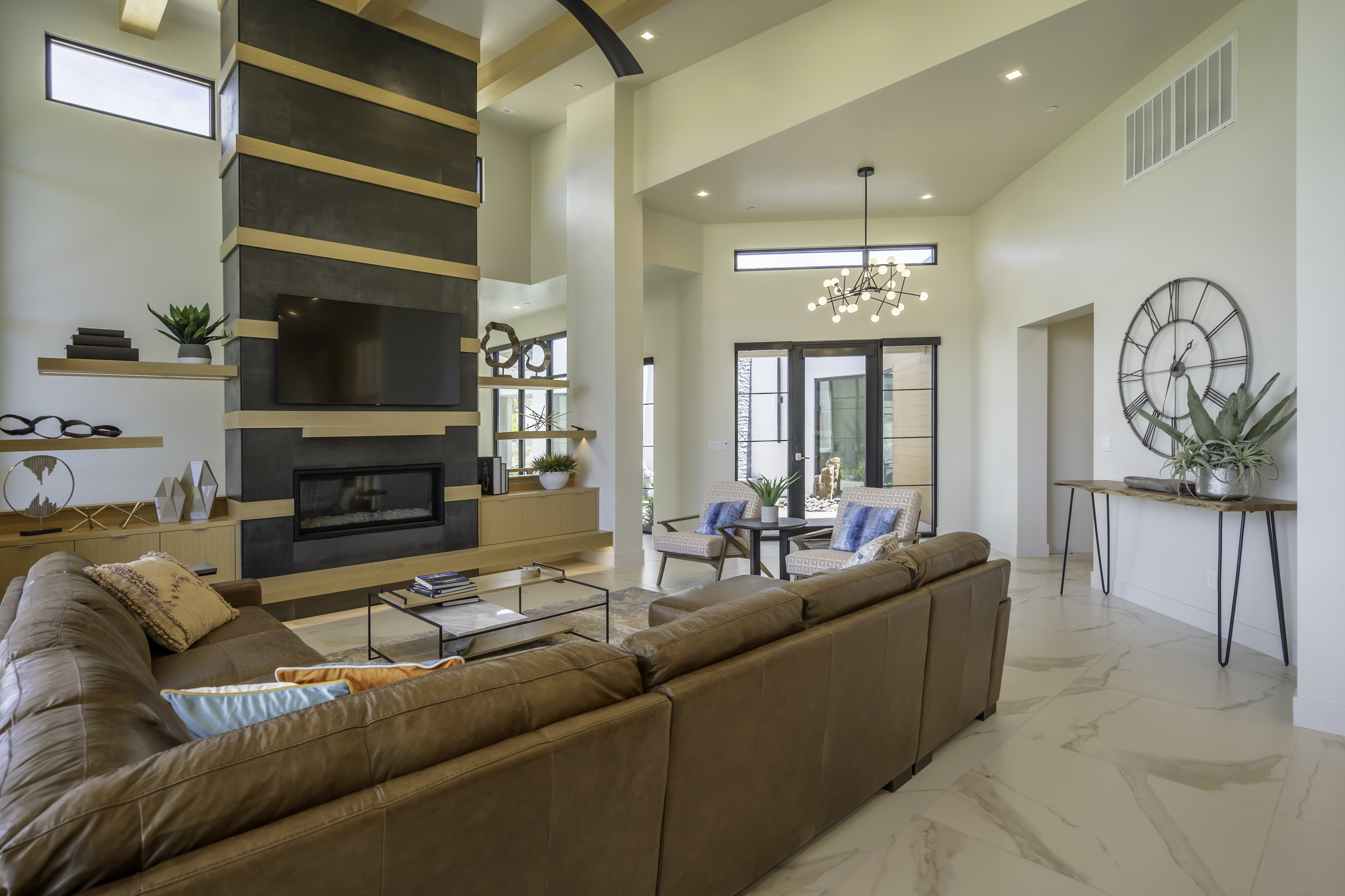 Living room with a fireplace, light marble finish floors, a high ceiling, and a chandelier
