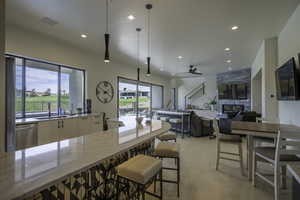 Kitchen featuring light stone countertops, pendant lighting, stainless steel dishwasher, ceiling fan, and modern cabinets