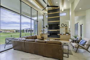 Living room featuring recessed lighting, a large fireplace, light marble finish floors, and a ceiling fan