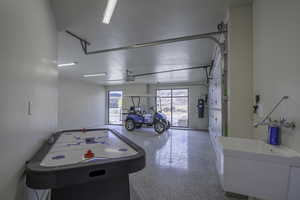 Game room with speckle patterned floor and a garage