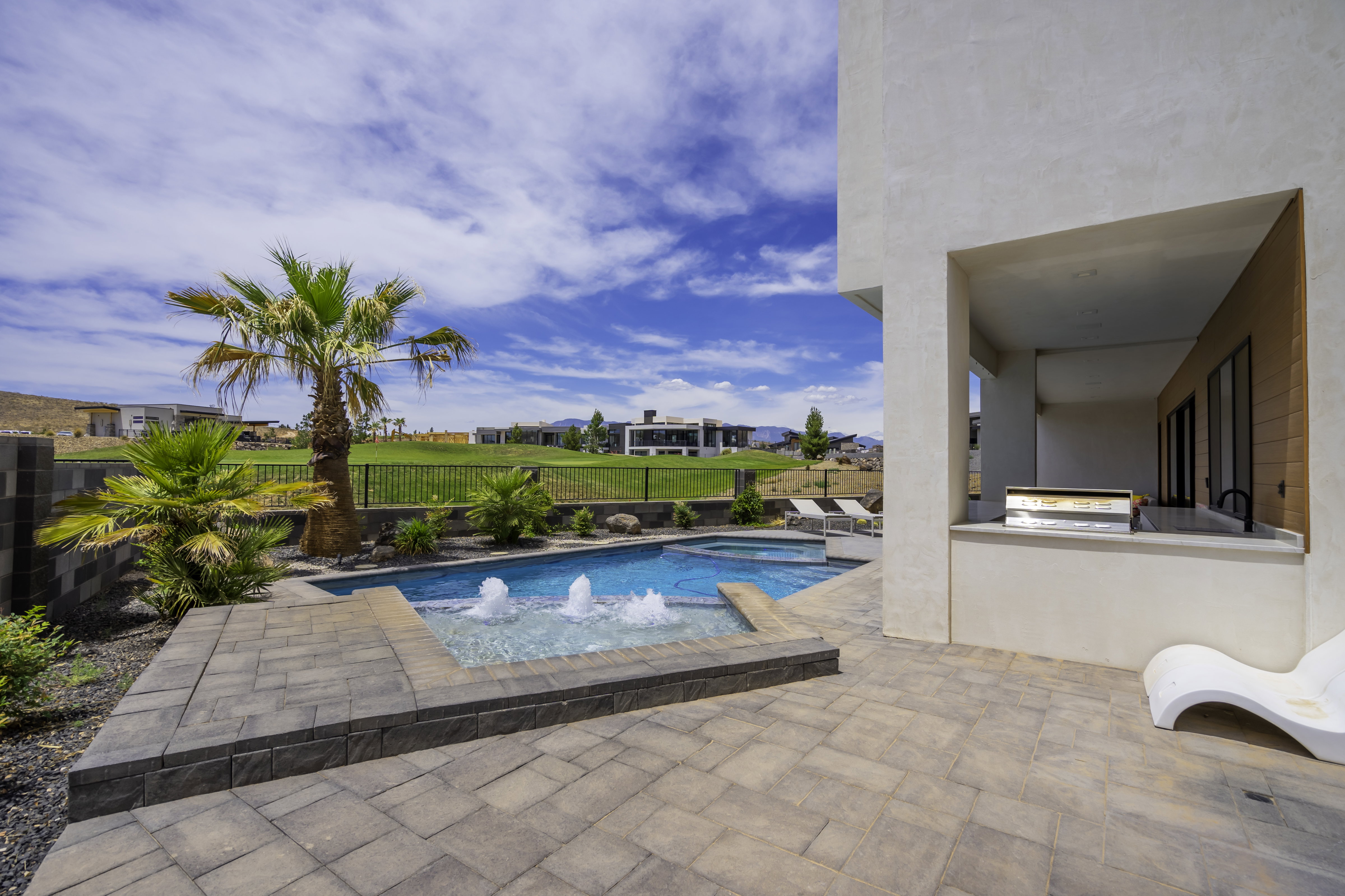 Combined pool / hot tub with a patio, area for grilling, a fenced backyard, and a residential view