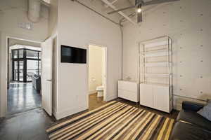 Bedroom featuring concrete floors, a ceiling fan, a high ceiling, and connected bathroom