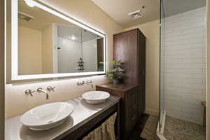 Bathroom featuring double vanity and tiled shower