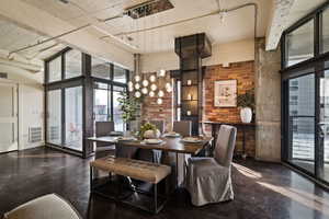 Dining room with concrete floors, healthy amount of natural light, floor to ceiling windows, a high ceiling, and brick wall