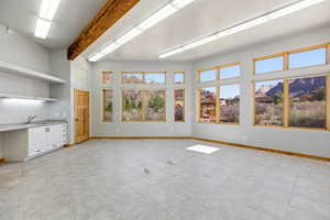 Unfurnished living room featuring baseboards and a sink