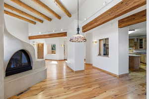 Unfurnished living room with beamed ceiling, a glass covered fireplace, and light wood-style floors