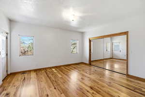 Unfurnished bedroom featuring light wood-style floors, a closet, and a textured ceiling