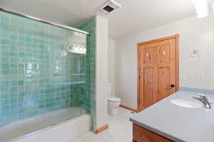 Full bath with vanity, light tile patterned flooring, and bath / shower combo with glass door