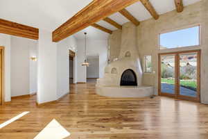Unfurnished living room with light wood-style flooring, a large fireplace, and french doors